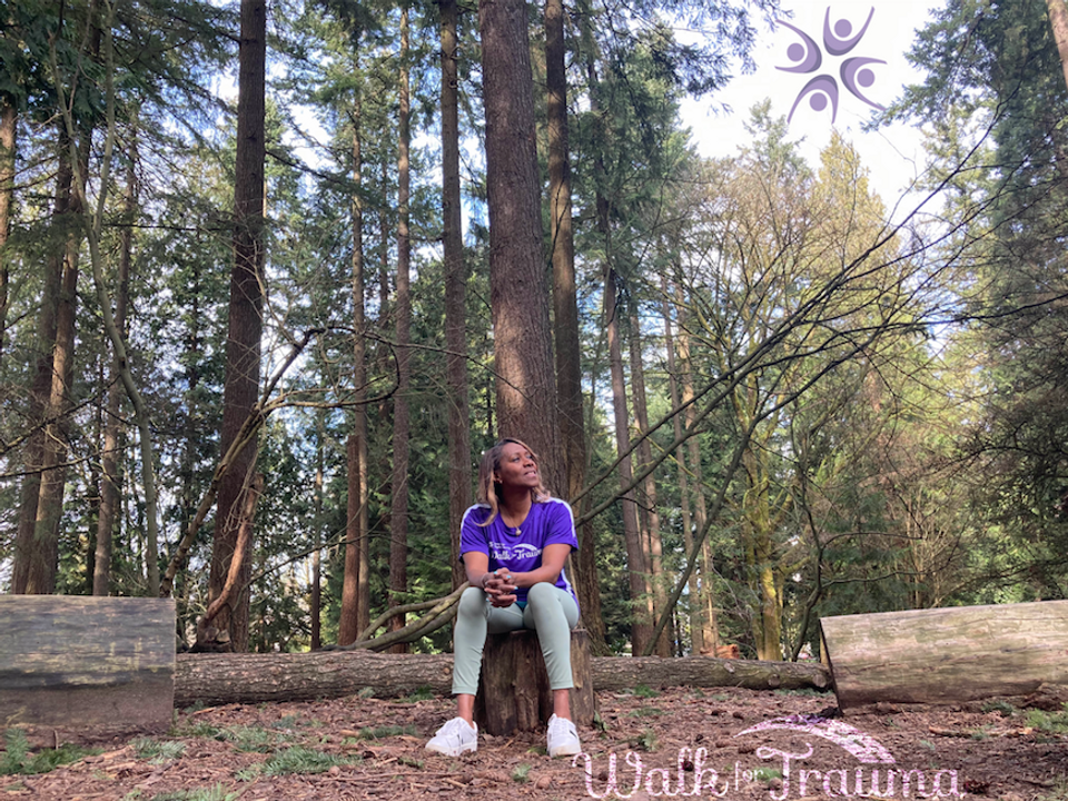 A woman wearing a Walk for Trauma shirt seated peacefully in the forest