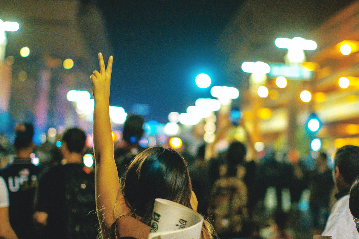 A person raising a peace sign in a gathered community